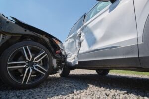 Close-up of two cars after a collision showing severe side damage on a silver vehicle.