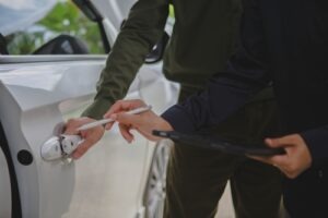 man reviewing car door damage with an insurance adjuster during a post-accident inspection