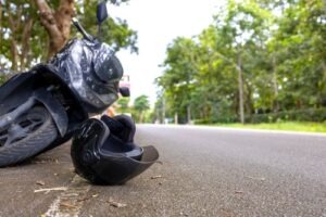 Motorcycle lying on the road with a fallen helmet in front of it after an apparent accident.