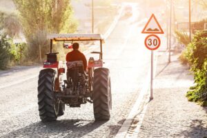 Tractor rides on the pavement road in the sunlight