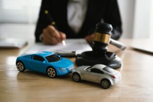 A Lawyer with two toy cars and Gavel on table