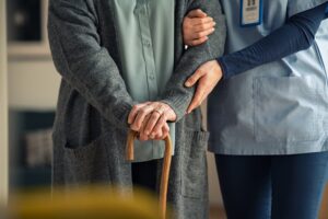 Close up hands of caregiver doctor helping old woman